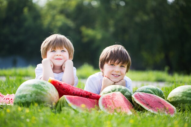 Lustige Jungen, die Wassermelone draußen im Sommerpark essen.