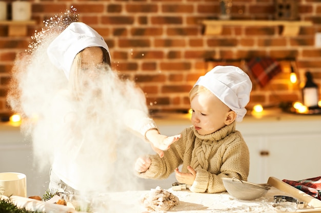 Lustige Kinder der glücklichen Familie bereiten den Teig zu