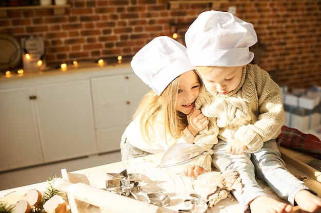 Lustige Kinder der glücklichen Familie bereiten den Teig zu