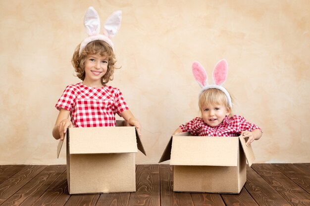 Lustige Kinder, die Osterhasen tragen. Kinder haben Spaß zu Hause