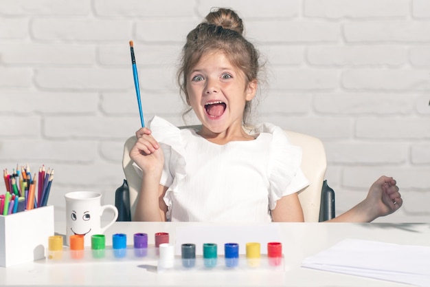 Lustige Kinder Emotionen kleine Mädchen zeichnen bunte Bilder mit Buntstiften im Schulklassenzimmer...