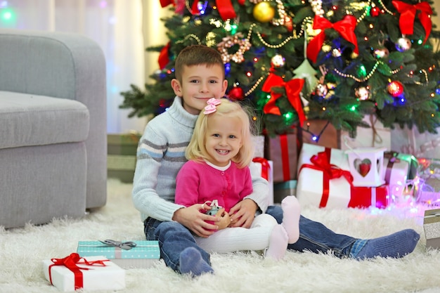 Lustige Kinder mit Geschenkboxen und Weihnachtsbaum