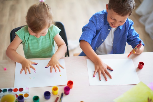 Lustige Kinder zeigen ihren Handflächen die gemalte Farbe.