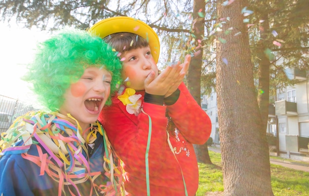 Lustige Kindermädchen feiern Karneval lächelnd und haben Spaß mit bunten Konfetti