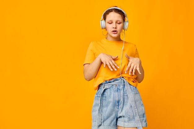 Lustige Mädchen gelbe T-Shirt Kopfhörer Unterhaltung Musik Spaß isolierte Hintergründe unverändert