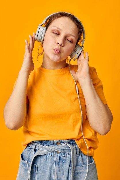 Lustige Mädchen gelbe T-Shirt Kopfhörer Unterhaltung Musik Spaß isolierte Hintergründe unverändert