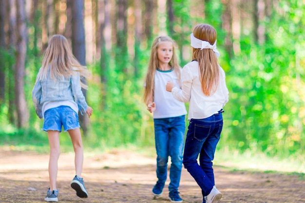 Lustige Mädchen spielen Blindekuh draußen im Wald