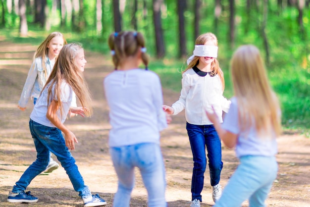 Lustige Mädchen spielen Blindekuh draußen im Wald