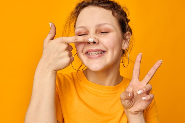 Lustige Mädchengesten mit den Händen Grimassen Emotionen gelber Hintergrund unverändert