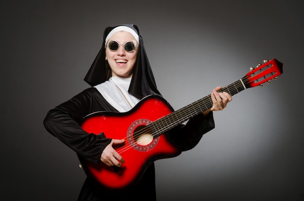 Lustige Nonne mit dem roten Gitarrenspielen