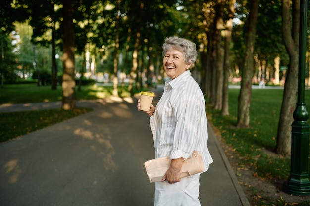 Lustige Oma trinkt Kaffee im Sommerpark