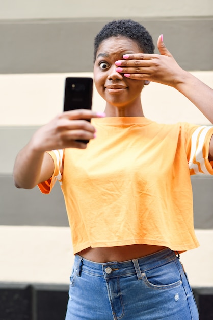 Lustige schwarze Frau, die draußen selfie Fotos mit glücklichem Ausdruck macht