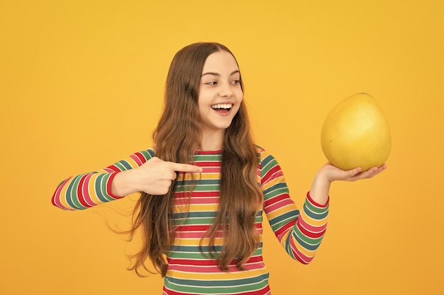 Lustige Teenager-Mädchen halten Zitrusfrüchte Pummelo oder Pampelmuse große grüne Grapefruit isoliert auf gelbem Hintergrund