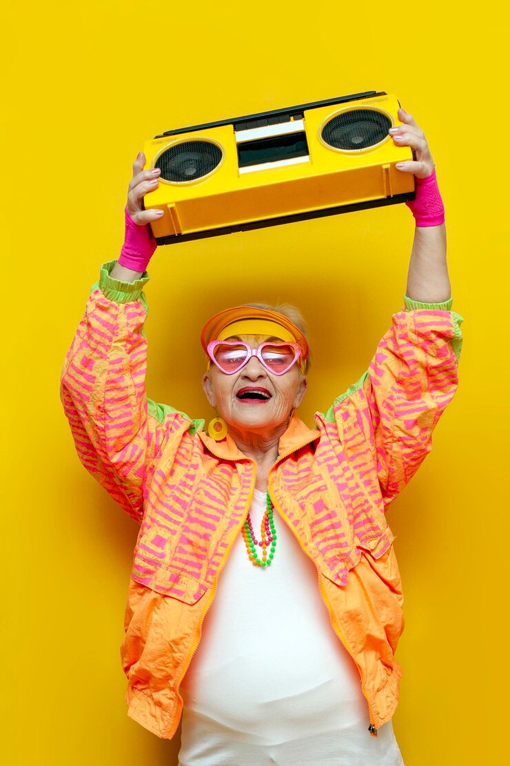 lustige verrückte alte Oma mit Tonbandgerät in sportlicher Hipsterkleidung hört Musik und singt auf gelbem Hintergrund
