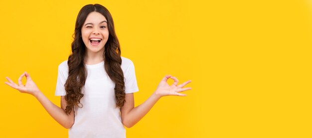 Lustige zwinkernde Teenager Kind Mädchen in weißem Hemd halten die Hände in Yoga om aum Geste entspannen meditieren versuchen ruhig Kind Gesicht horizontal Poster Teenager Mädchen isoliert Porträt Banner mit Kopierraum