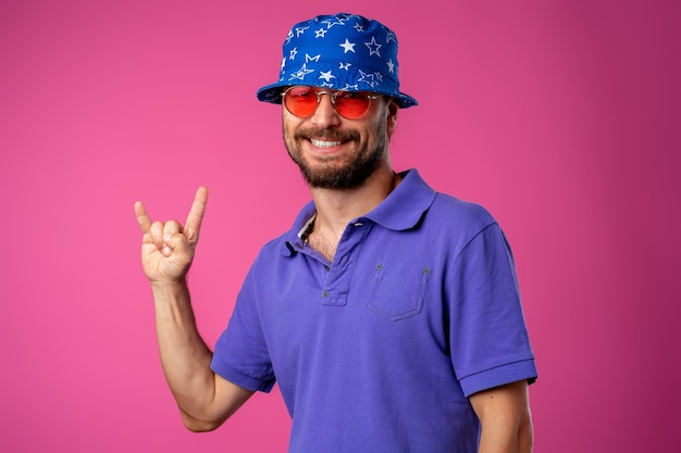 Lustiger bärtiger Smiley-Mann, der Strandhut und Sonnenbrille gegen rosa Hintergrund trägt