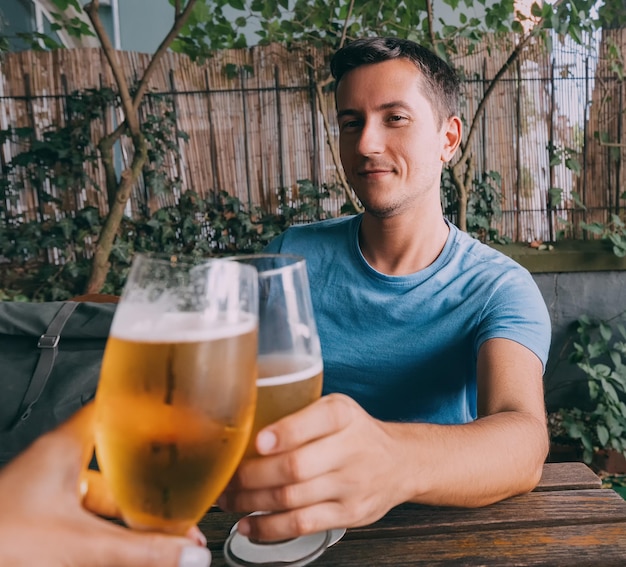 Foto lustiger betrunkener mann klirrt in einer bar, kneipe oder einem deutschen biergarten mit frisch gebrauten hellen biergläsern