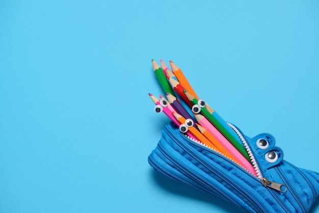 Lustiger Bleistiftkasten, der Bleistifte auf Blau isst