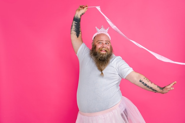 Lustiger dicker Mann, der vorgibt, eine Ballerina mit Tutu auf einer rosa Wand zu sein