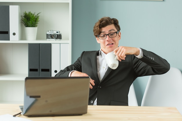 Lustiger Geschäftsmann, der Tee im Büro verschüttet