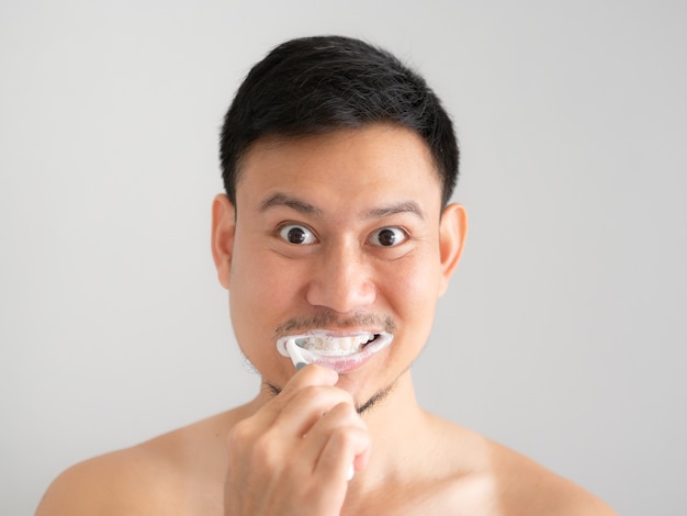 Lustiger Gesichtsmann putzt seine Zähne mit Schaum über seinem Gesicht.