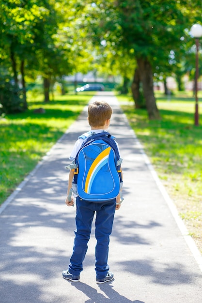 lustiger glücklicher Schuljunge Gesicht zurück zur Schule süßes Kind mit Rucksack läuft