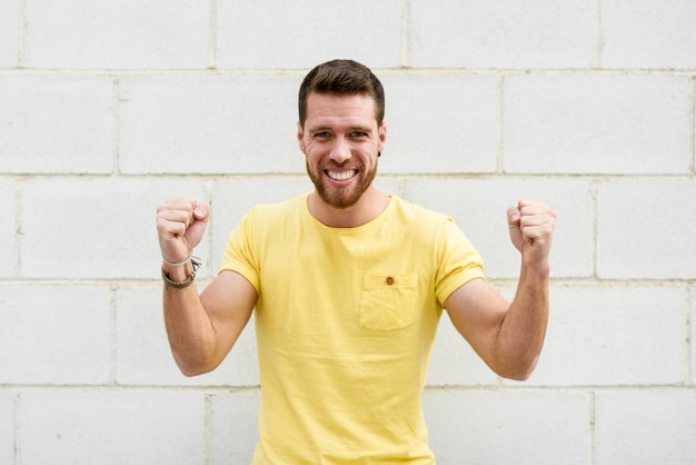 Lustiger junger Mann auf Backsteinmauer mit lustigem Ausdruck.