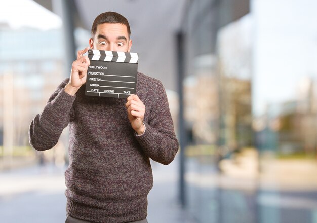 Lustiger junger Mann mit einem clapperboard