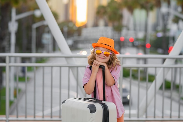 Lustiger Kinderreisender-Junge und Reisekoffer-Kind mit Reisepass für Urlaubskinderreise litt