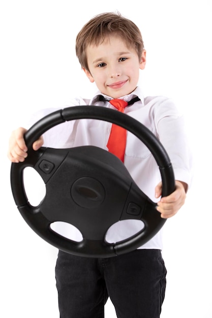 Lustiger kleiner Junge hält ein Auto-Lenkrad Junger Fahrer auf einem weißen Hintergrund