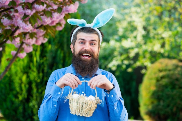 Lustiger Mann, der Ostereier jagt Porträt des Ostermannes hält Korb mit Ostereifrühlingsferien