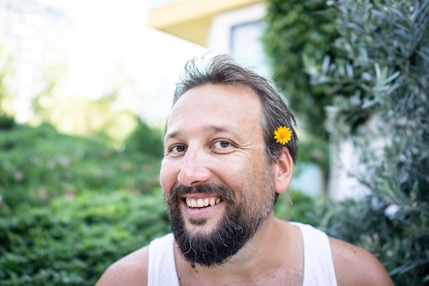 Lustiger Mann mit Blume in der Nase, der im Garten lacht