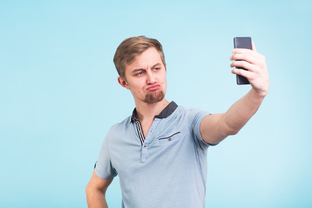 Lustiger Mann verzog das Gesicht, während er Selfie auf Blau machte