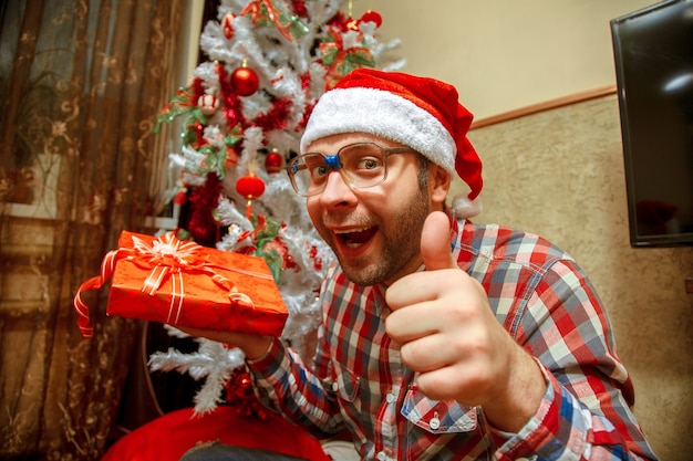 Lustiger Nerd in Sankt-Hut bekommt Weihnachtsgeschenke. Weihnachtsstimmung. Neujahr.