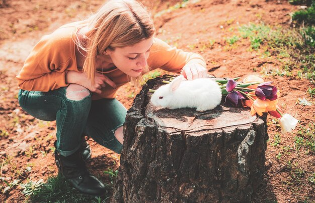 Lustiger Osterhase. Kleines Mädchen, das sich auf der Ostereiersuche amüsiert. Glückliches lächelndes kleines jugendlich Mädchen mit dem Häschen, das Ostereier jagt.