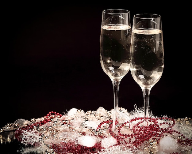 Lustiger Schneemann und zwei Gläser Champagner auf schwarzem Hintergrund