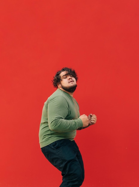 Lustiger übergewichtiger junger Mann, der Hip-Hop auf einem roten Wandhintergrund tanzt