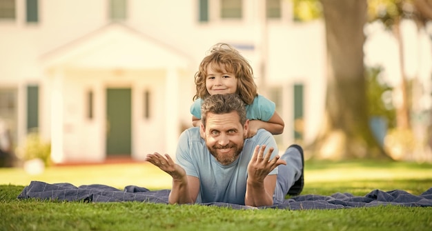 Lustiger Vater mit Sohn entspannen sich zusammen auf grüner Parkgrasfreundschaft