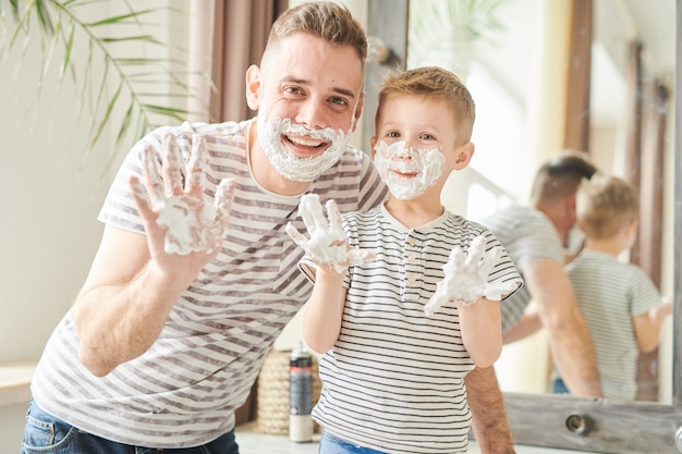 Lustiger Vater und Sohn bedeckt mit Rasierschaum