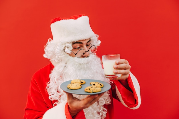 Lustiger Weihnachtsmann mit Keksen und einem Glas Milch