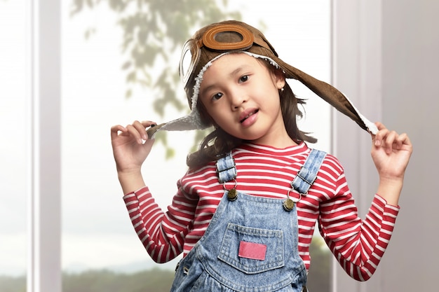 Lustiges asiatisches Kind mit dem Fliegerhut- und -schutzbrillenspielen