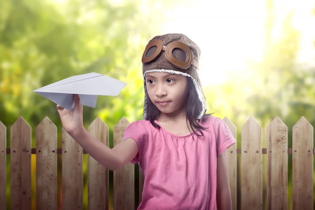 Lustiges asiatisches kleines Mädchen im Fliegersturzhelm, der Spielzeugflugzeug spielt