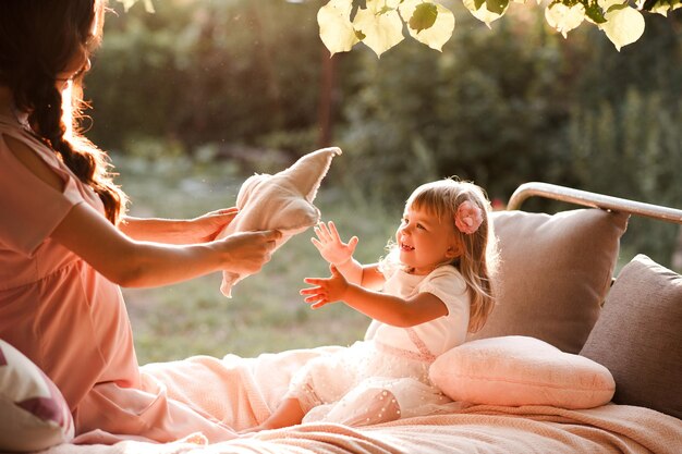 Lustiges Baby, das mit Mutter im Bett über Naturhintergrund spielt