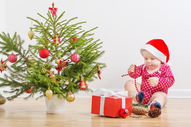 Lustiges Baby mit kleiner Weihnachtstanne zu Hause