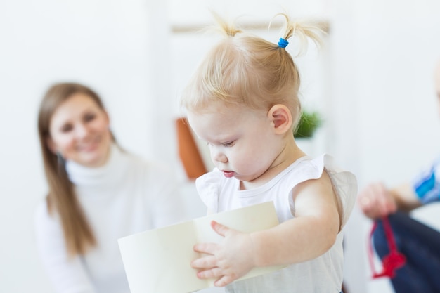 Lustiges Babykleinkindmädchen, das im Wohnzimmer spielt. Kinder- und Familienkonzept.