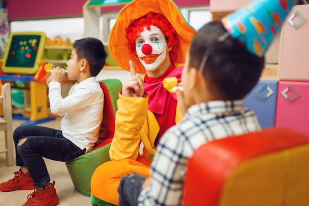 Lustiges Clownspiel mit fröhlichen Kindern zusammen. Geburtstagsfeier im Spielzimmer feiern