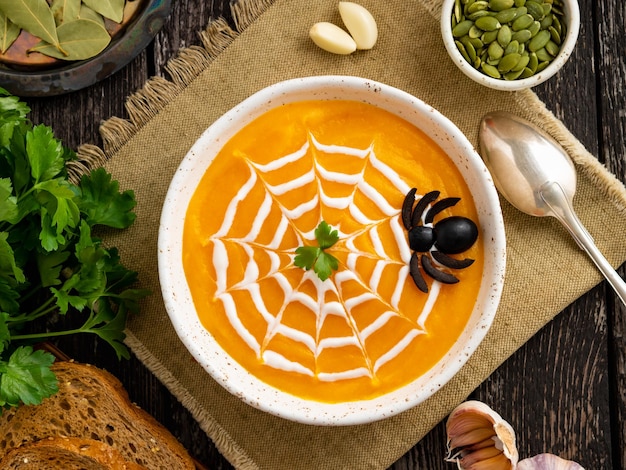 Lustiges Essen für Halloween-Kürbispüreesuppe Spinnennetz dunkle alte Holztischplatte