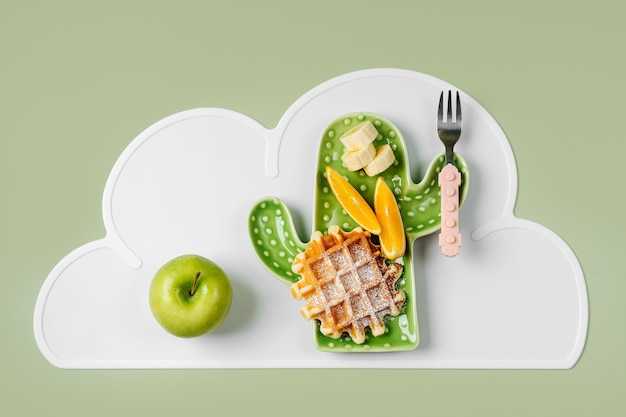 Lustiges Essen für Kinder. Kinderfrühstück. Teller in Form eines Kaktus mit Waffeln und Früchten. Essensidee für Kinder.