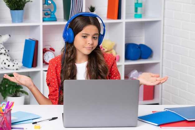 Lustiges Gesicht Schülerin der Schule, die beim Lernen mit dem Laptop am Tisch sitzt Glückliches Mädchengesicht positiv