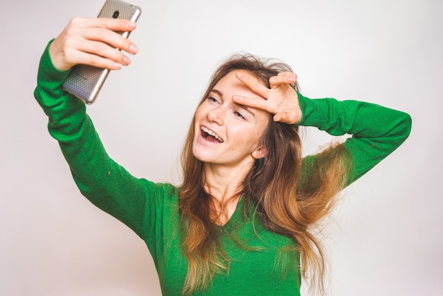 Lustiges Gesicht Teen macht Selfie und zeigt zwei Daumen Friedenssymbol